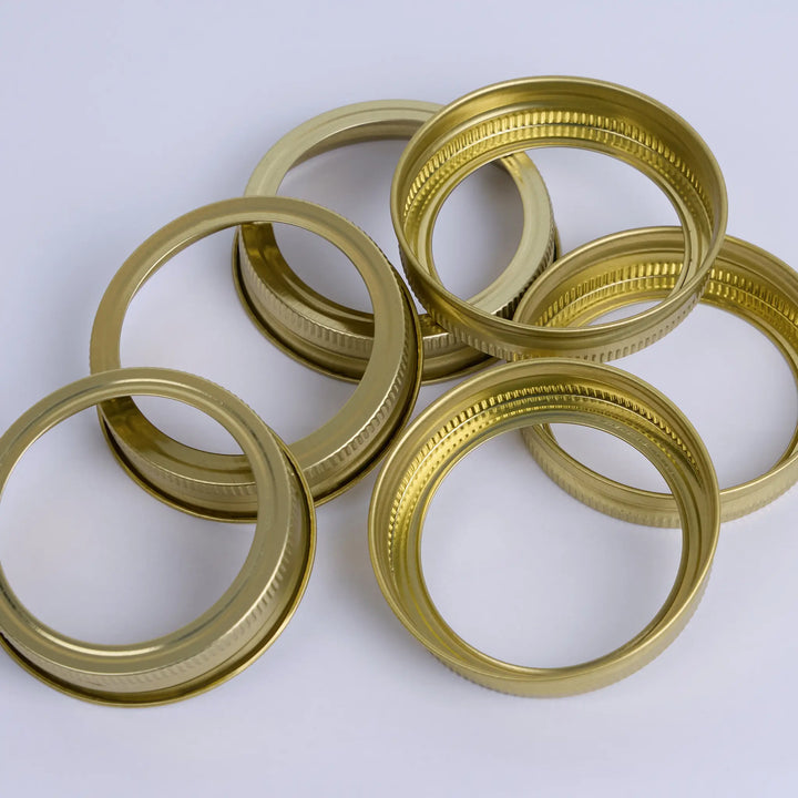 Gold canning rings for mason jars on a white background