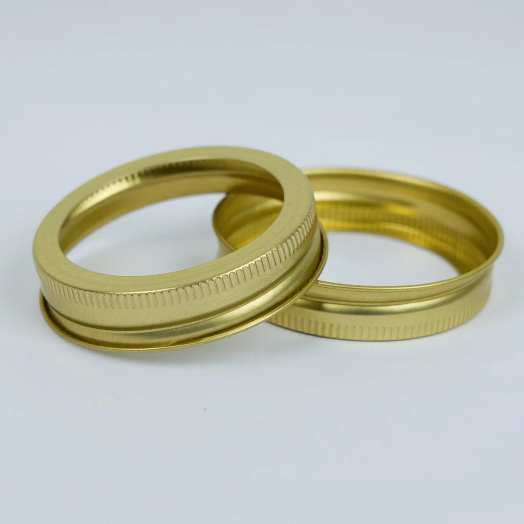 Two gold metal canning jar bands on a white background