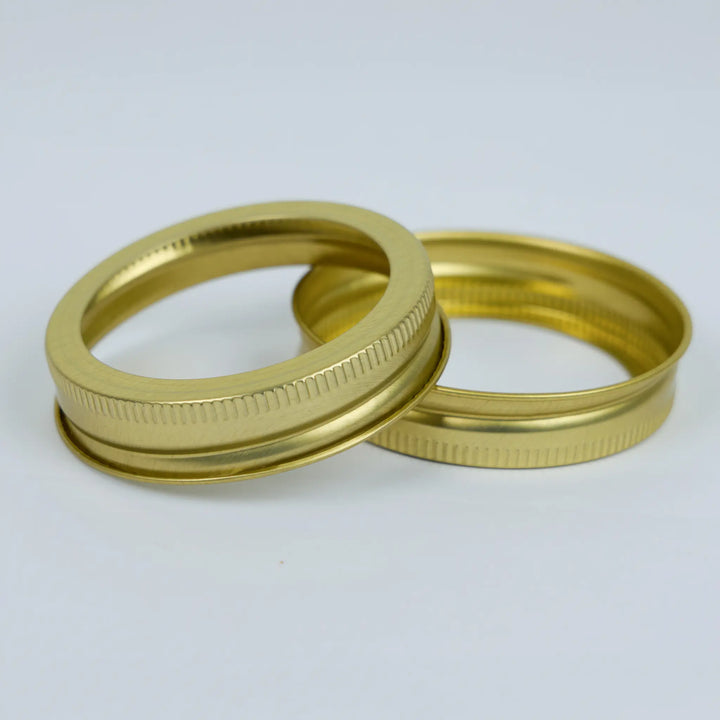 Two gold metal canning jar bands on a white background