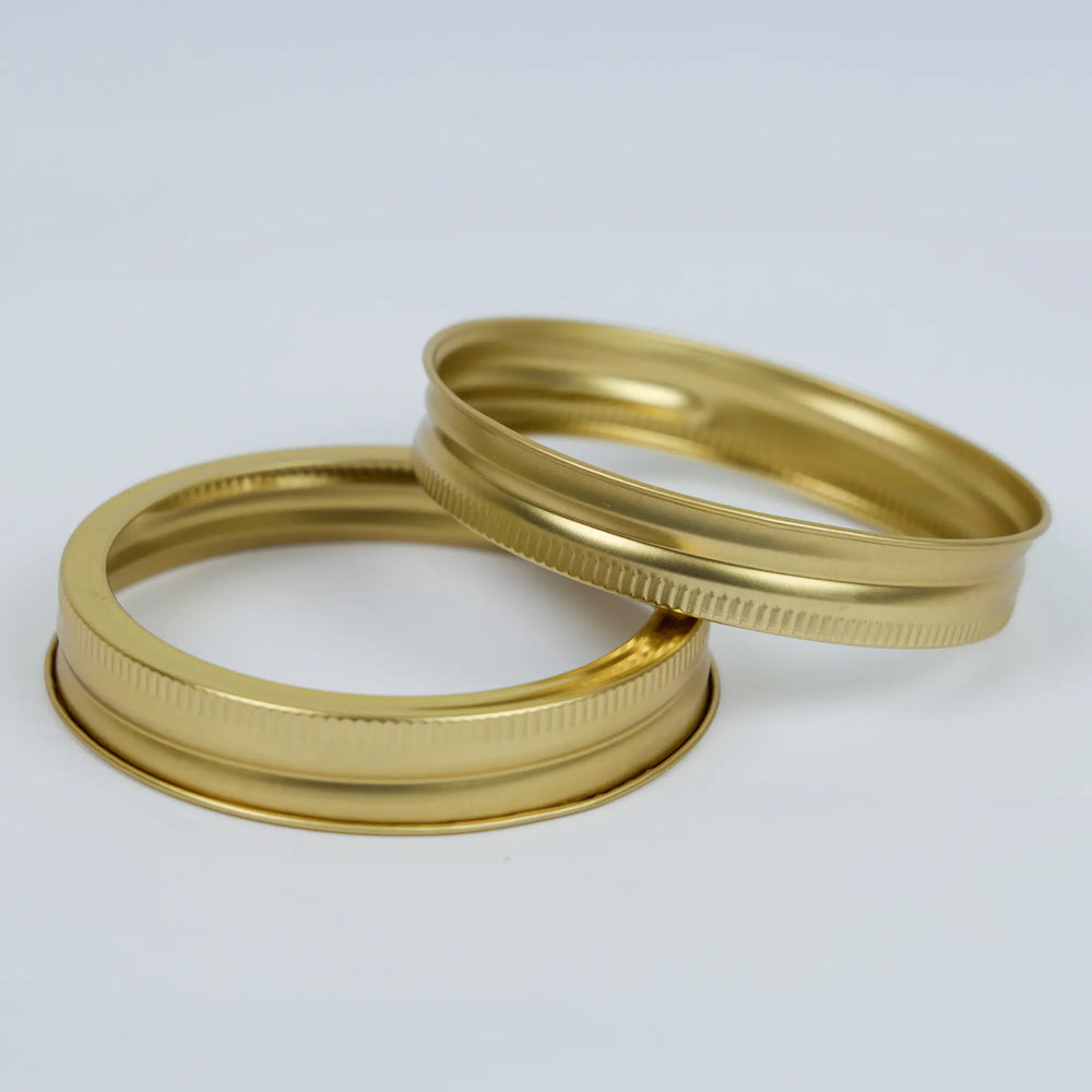 Two gold metal canning rings stacked on a white background