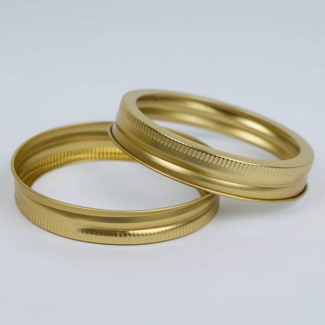 Two brass metal mason jar bands stacked on a white background
