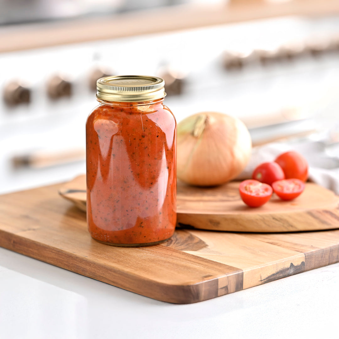 Jar of red sauce on a wooden cutting board with tomatoes and an onion in the background Canned tomato sauce in Superb jar with label Regular mouth quart canning jar set on kitchen counter Durable regular mouth jars made for home canning