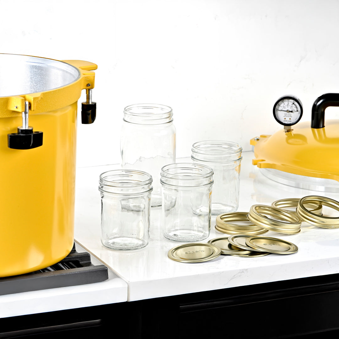 Yellow canner on a stove with clear jars and gold lids on a white surface Assorted sizes of Superb canning jars Assorted sizes of Superb canning lids High-quality canning jars for food storage Canning jars set on kitchen counter High-performance yellow pressure canner